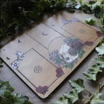 Tarot spread board with a cat skull surrounded by flowers and Ivy leaves, engraved wood