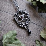 Pendentif triquetra elfique orné d'entrelacs celtiques, d'un grenat rouge et de cristaux noirs, bijou gothique artisanal