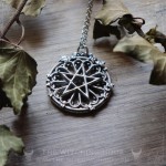 Pendentif pentacle sur rosace de cathédrale gothique entouré de feuilles de lierres