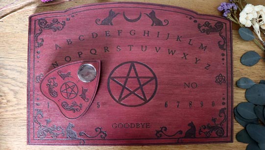 Red wooden ouija board with cats